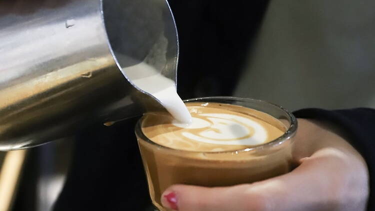 Close-up of milk being poured into coffee in a café. Close-up of milk being poured into coffee in a café.