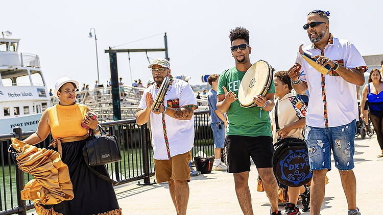 Wide view of musicians performing along a waterfront promenade. Wide view of musicians performing along a waterfront promenade.