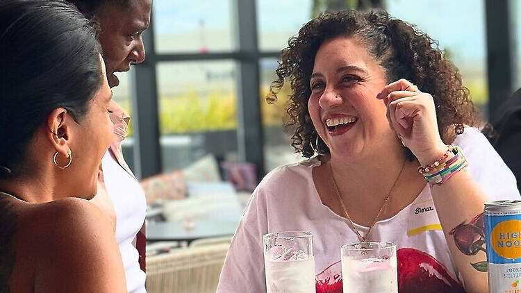 A close-up of people laughing and talking around a table at a restaurant. A close-up of people laughing and talking around a table at a restaurant.