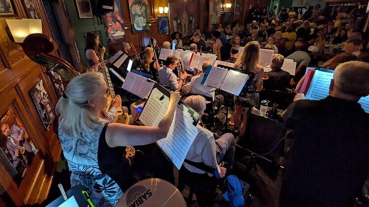 A wide shot of musicians performing for an audience in a restaurant A wide shot of musicians performing for an audience in a restaurant