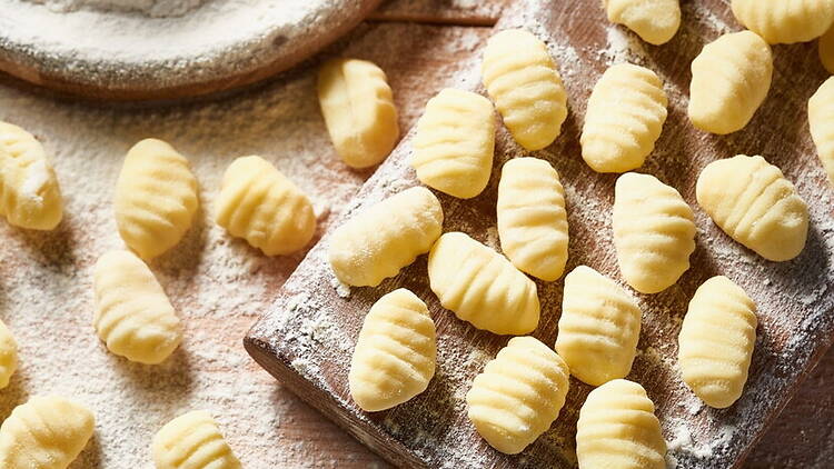 Close-up of uncooked gnocchi on a floured wooden board. Close-up of uncooked gnocchi on a floured wooden board.
