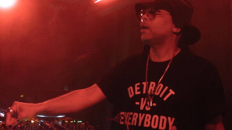 Close-up of a DJ performing at a mixing console in a dimly lit club. Close-up of a DJ performing at a mixing console in a dimly lit club.
