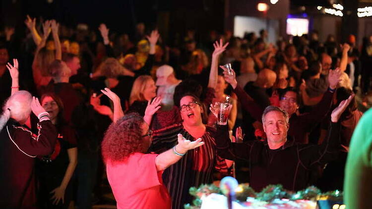Wide shot of people dancing and cheering at an indoor party. Wide shot of people dancing and cheering at an indoor party.