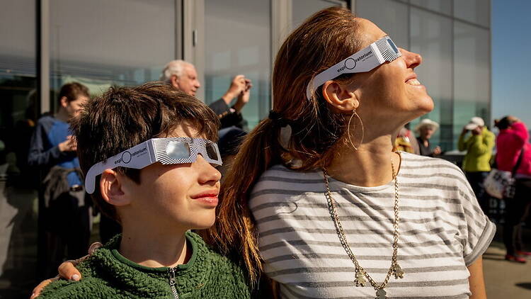 A close-up of people wearing eclipse glasses while looking at the sky outdoors.