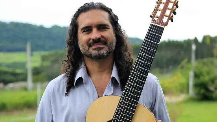 A close-up of a person holding a guitar outdoors. A close-up of a person holding a guitar outdoors.