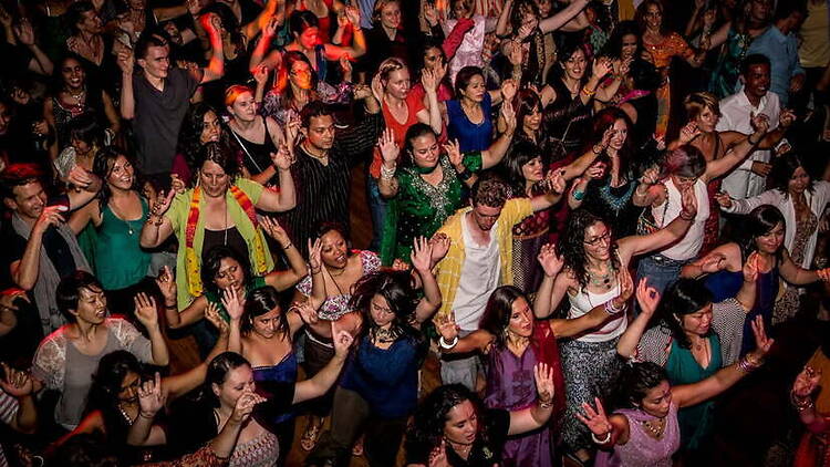 A wide shot of people dancing at an indoor event. A wide shot of people dancing at an indoor event.