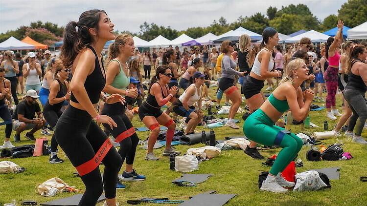A wide shot of people exercising together on a lawn at an outdoor fitness event