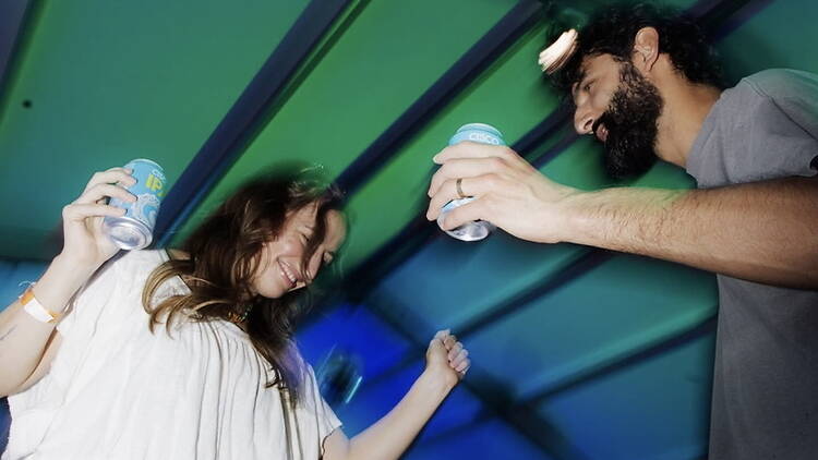 Close-up of two people dancing with drinks at an indoor party. Close-up of two people dancing with drinks at an indoor party.