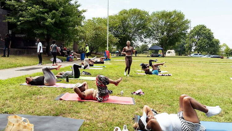 Wide shot of people exercising on yoga mats in a park. Wide shot of people exercising on yoga mats in a park.