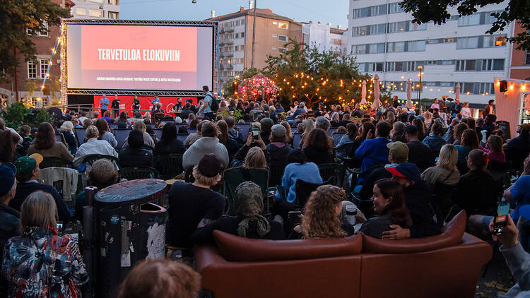 ihmisiä istuu ulkosalla katsomassa elokuvaa valkokankaalta ihmisiä istuu ulkosalla katsomassa elokuvaa valkokankaalta