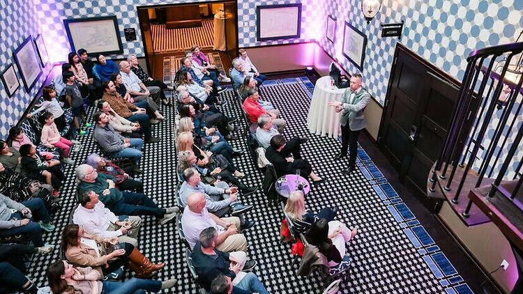 A wide shot of people watching a magic show in a theatre