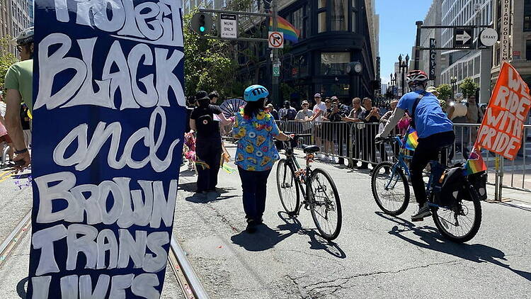 A wide shot of people walking and cycling in a Pride parade.