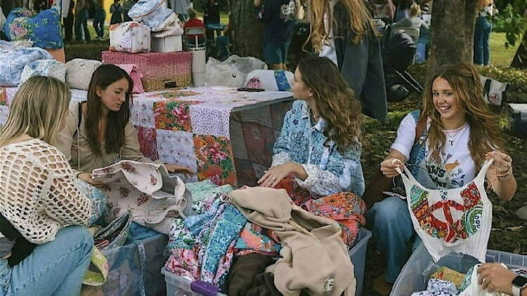 A wide shot of people sorting fabric at an outdoor craft event.