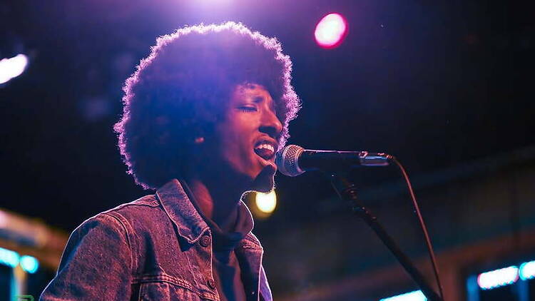 A close-up of a singer performing into a microphone under stage lights A close-up of a singer performing into a microphone under stage lights