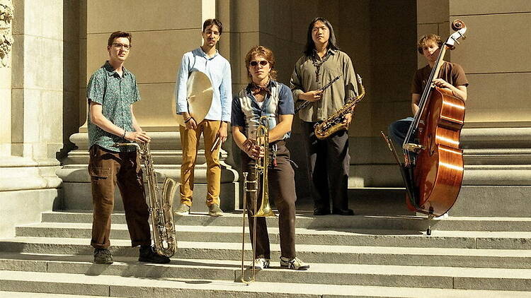 A wide shot of a jazz band posing with instruments on building steps