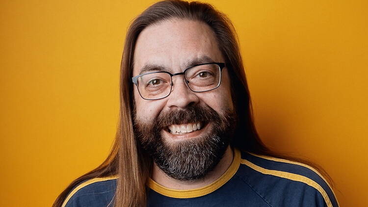 Close-up of a smiling person posing against a yellow background.