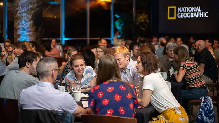 A wide shot of people socializing at an indoor event venue. A wide shot of people socializing at an indoor event venue.