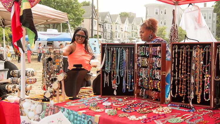 A wide shot of vendors displaying jewelry at an outdoor market.