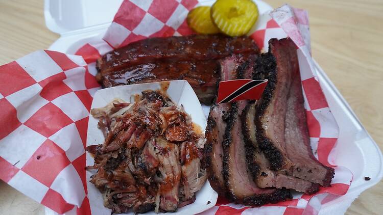 A takeout container of brisket, pulled pork and ribs