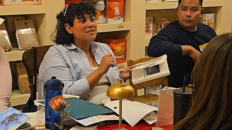 A wide shot of two people discussing materials at a table during a workshop.
