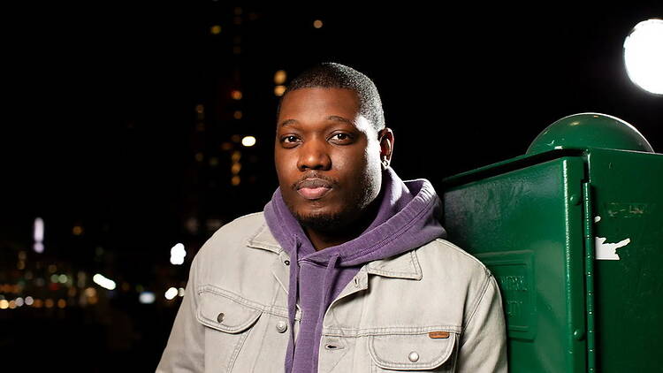 Close-up of a person posing outdoors at night beside a green utility box.