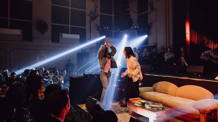 Now or Never Two people on stage in action surrounded by an audience.