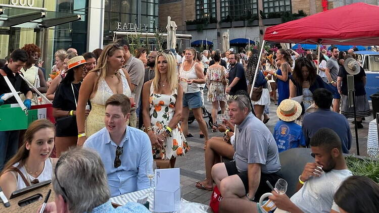 A wide shot of people dining and socializing at an outdoor street event A wide shot of people dining and socializing at an outdoor street event
