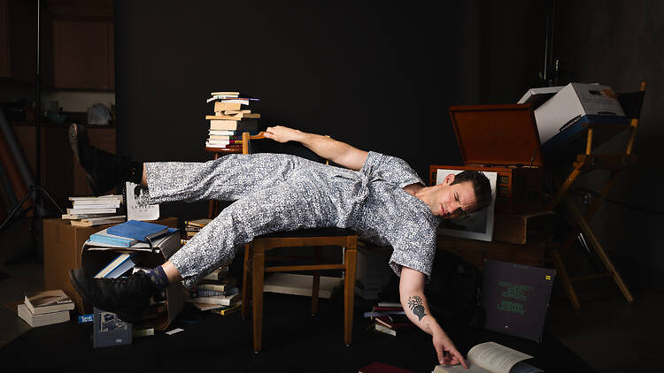 Melbourne Fringe Festival A man lying across a chair surrounded by books.