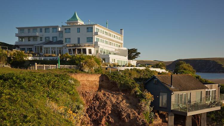 The exterior of Burgh Island hotel, on the top of a hill with natural landscapes in the background 