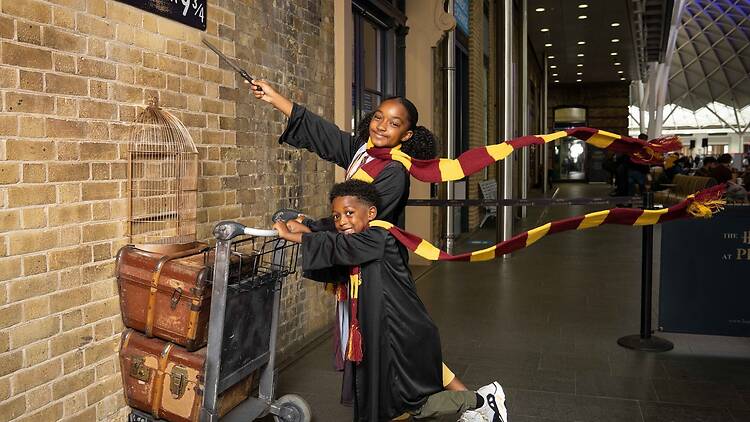 Two children having a photo taken at Platform 9 3/4 in King’s Cross Two children having a photo taken at Platform 9 3/4 in King’s Cross