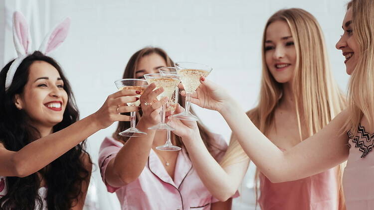 A medium shot of four women toasting with glasses at a celebration.