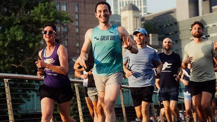 A wide shot of runners jogging together on a city bridge.