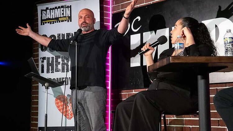 A wide shot of comedians speaking into microphones on stage at a comedy show A wide shot of comedians speaking into microphones on stage at a comedy show