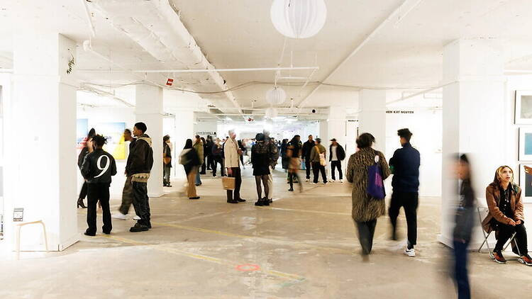 Wide shot of people viewing artwork in a spacious indoor gallery. Wide shot of people viewing artwork in a spacious indoor gallery.