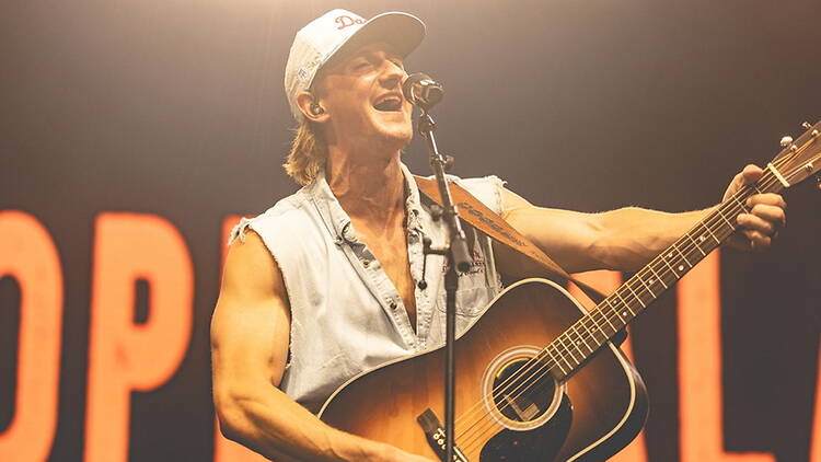 Close-up of a musician playing an acoustic guitar and singing on a concert stage Close-up of a musician playing an acoustic guitar and singing on a concert stage
