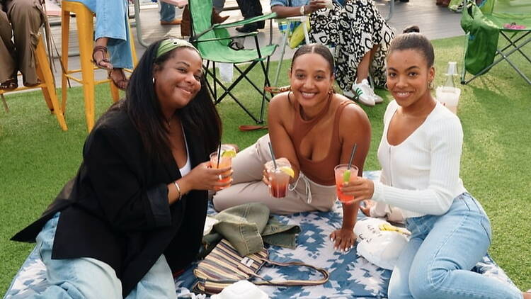 Close-up of three people holding drinks while sitting on a picnic blanket outdoors Close-up of three people holding drinks while sitting on a picnic blanket outdoors