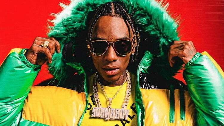 Close-up of a person wearing a fur-lined jacket and sunglasses against a red backdrop Close-up of a person wearing a fur-lined jacket and sunglasses against a red backdrop