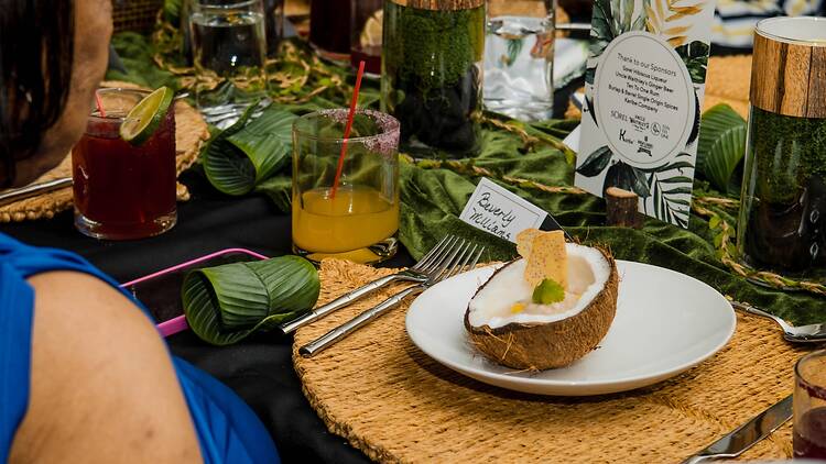 Proppa Suppa A table with a coconut on it with ceviche inside