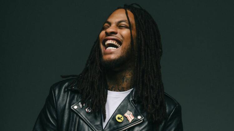Close-up of a musician laughing while wearing a leather jacket against a dark background. Close-up of a musician laughing while wearing a leather jacket against a dark background.