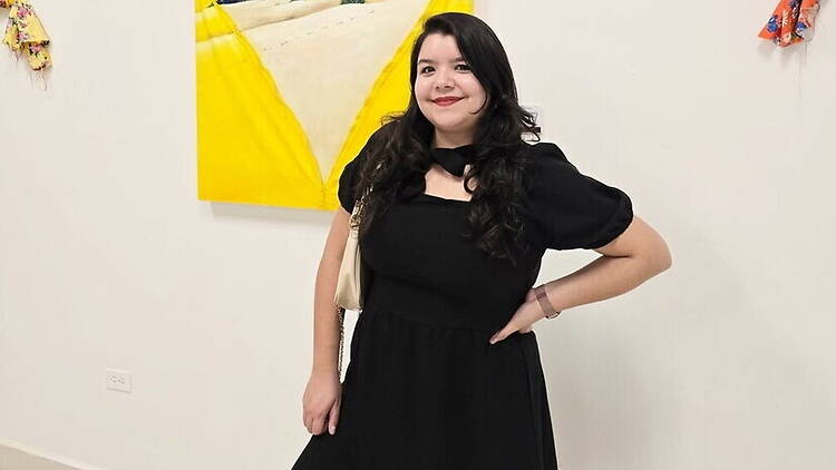 A woman in a black dress poses with one hand on her hip in an art gallery. A woman in a black dress poses with one hand on her hip in an art gallery.