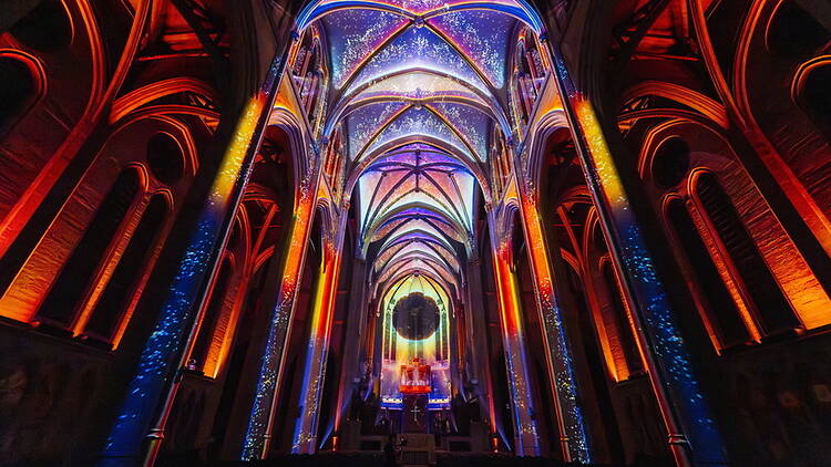 A wide shot of a colorful cathedral interior with illuminated arches and a starry ceiling. A wide shot of a colorful cathedral interior with illuminated arches and a starry ceiling.