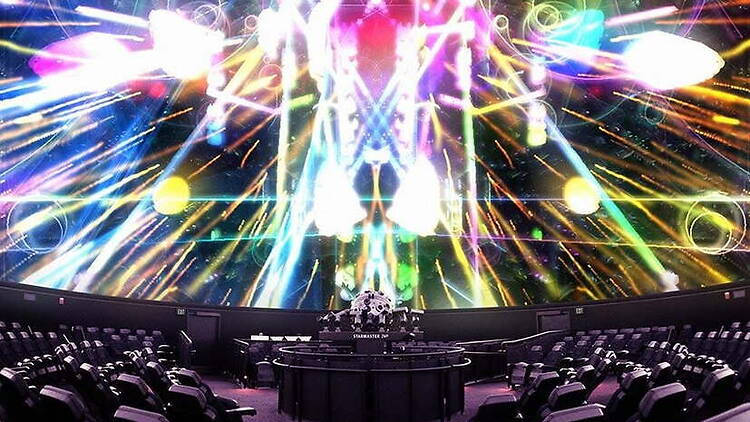 A wide shot of an immersive screen displaying colorful light patterns in an auditorium.