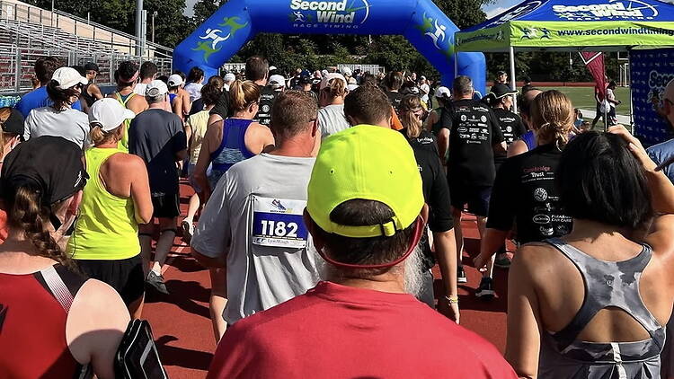 A wide shot of runners gathering at the starting line of a race on a track.
