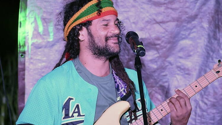 Close-up of a musician playing bass guitar and singing into a microphone on stage. Close-up of a musician playing bass guitar and singing into a microphone on stage.
