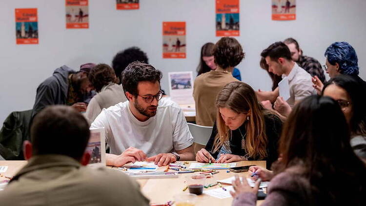 A wide shot of people collaborating on art projects at tables in a community room