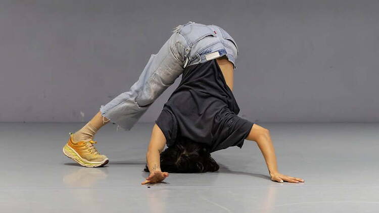 A wide shot of a dancer performing a floor move in a studio