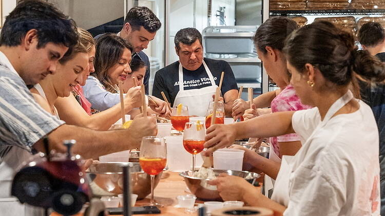 A wide shot of people mixing ingredients during a cooking class in a kitchen
