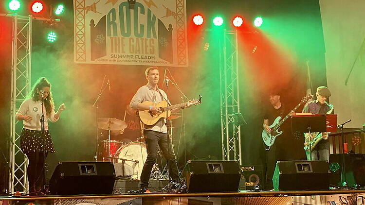 A wide shot of musicians performing on stage under colorful lights.