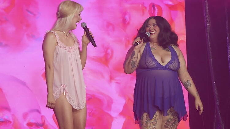 A wide shot of two people performing on stage with microphones.