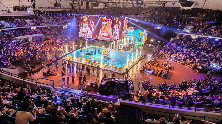 A wide shot of a Pokémon competition in a packed arena.